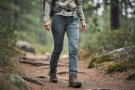 Woman hiking on a forest trail wearing women-specific hiking pants with a comfortable, movement-ready fit.
